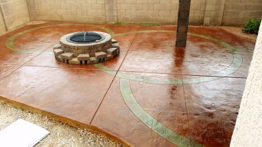 concrete patio stained and designed with firepit and stone pillar